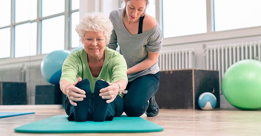Oudere dame doet rek- en strekoefeningen bij yoga